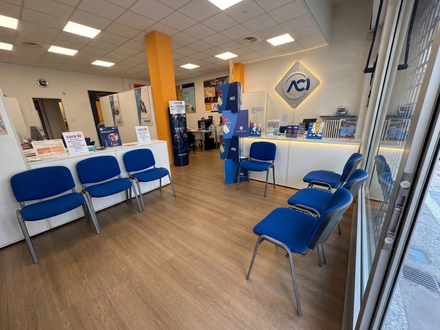 Interno della Delegazione ACI Moncalieri: sala d'attesa con sedute, reception e logo ACI